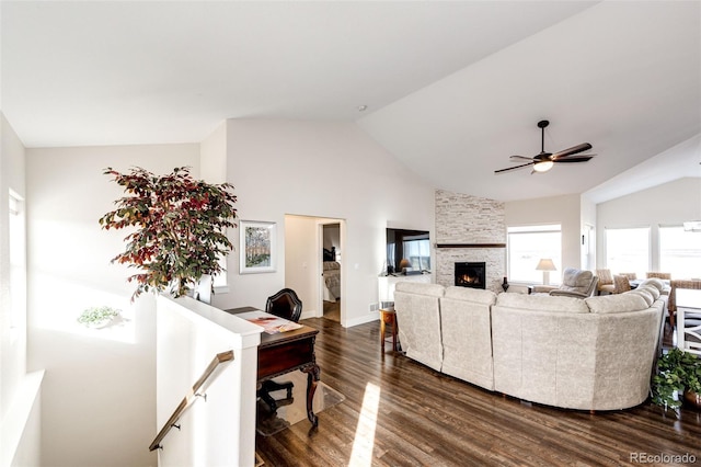 living room featuring baseboards, dark wood finished floors, a ceiling fan, a stone fireplace, and high vaulted ceiling