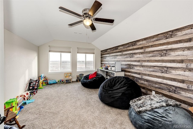 rec room featuring vaulted ceiling, carpet, a ceiling fan, and wooden walls