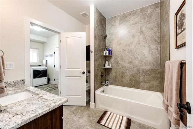 bathroom with shower / bath combination, visible vents, toilet, vanity, and washer / dryer