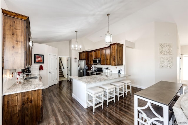 4820 S County Road 137, Bennett, CO 80102 - kitchen with appliances with stainless steel finishes, lofted ceiling, light stone counters, a peninsula, and dark wood-style floors
