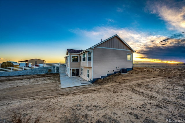 4820 S County Road 137, Bennett, CO 80102 - back of house at dusk featuring board and batten siding, a patio area, cooling unit, and fence
