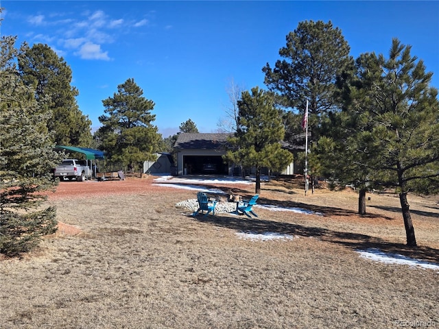 view of yard with dirt driveway and a carport