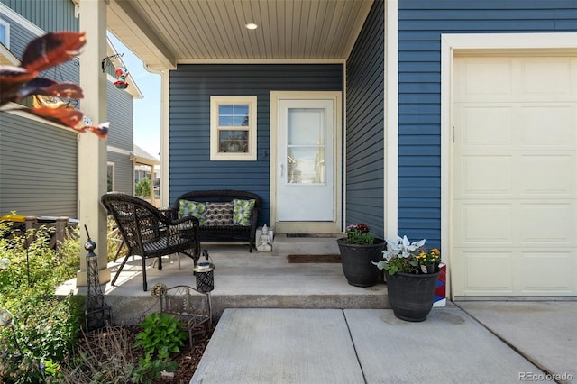 view of exterior entry featuring a garage and a porch