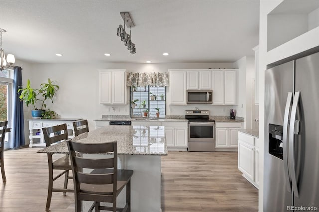 kitchen with stainless steel appliances, pendant lighting, white cabinetry, and a center island