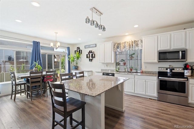 kitchen featuring appliances with stainless steel finishes, white cabinets, a kitchen island, and decorative light fixtures