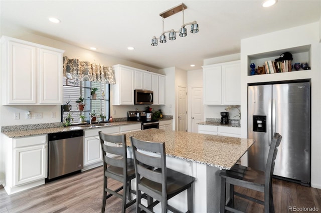 kitchen featuring a center island, pendant lighting, sink, appliances with stainless steel finishes, and white cabinets