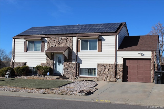 split level home with solar panels and a garage