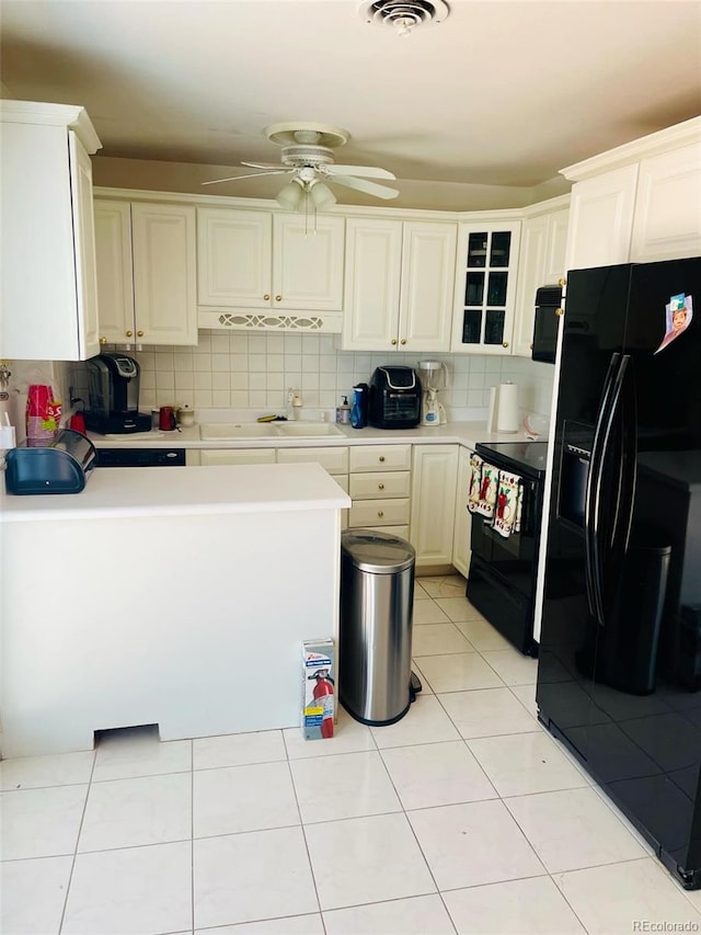 kitchen featuring decorative backsplash, light tile patterned floors, white cabinets, and black appliances