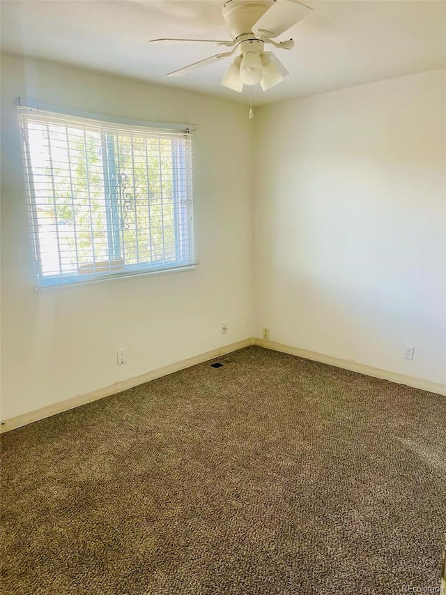 carpeted spare room featuring ceiling fan and plenty of natural light