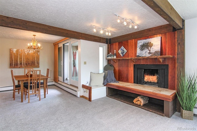 101 Ryan Gulch Ct Unit A202, Silverthorne, CO 80498 - dining space with carpet, a textured ceiling, a chandelier, beamed ceiling, and a warm lit fireplace