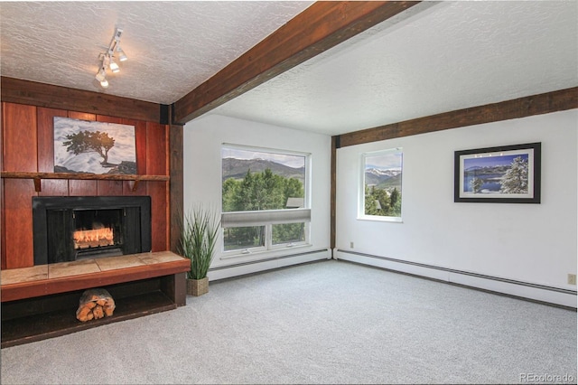 101 Ryan Gulch Ct Unit A202, Silverthorne, CO 80498 - unfurnished living room featuring a textured ceiling, carpet floors, beamed ceiling, a baseboard heating unit, and a lit fireplace