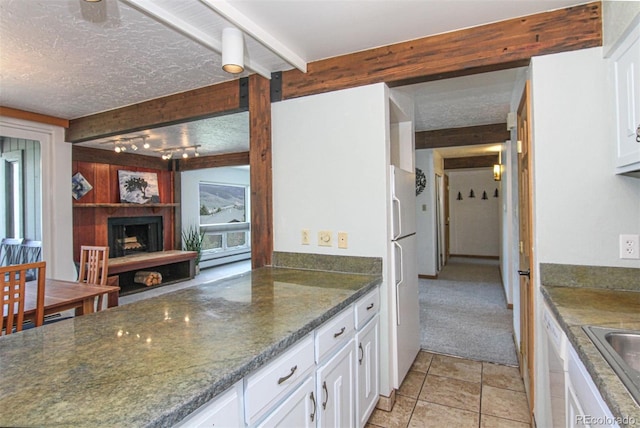 101 Ryan Gulch Ct Unit A202, Silverthorne, CO 80498 - kitchen featuring beamed ceiling, white cabinets, a large fireplace, a textured ceiling, and dark stone countertops