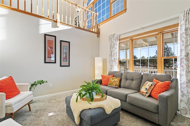 living area with carpet, a towering ceiling, and baseboards