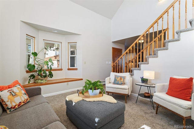 carpeted living area featuring high vaulted ceiling, baseboard heating, stairway, and baseboards