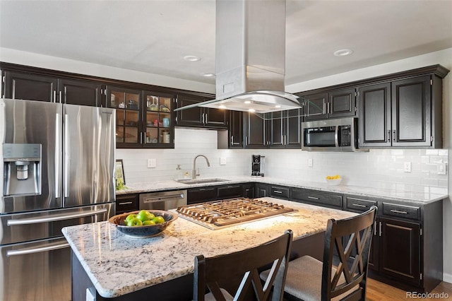 kitchen featuring stainless steel appliances, a sink, decorative backsplash, and island exhaust hood