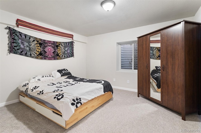 bedroom featuring light carpet, a textured ceiling, and baseboards