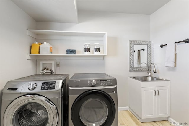 laundry area featuring light wood finished floors, cabinet space, washing machine and dryer, a sink, and baseboards