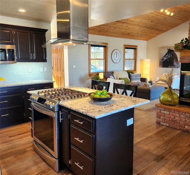 kitchen with island range hood, decorative backsplash, appliances with stainless steel finishes, open floor plan, and light wood-type flooring