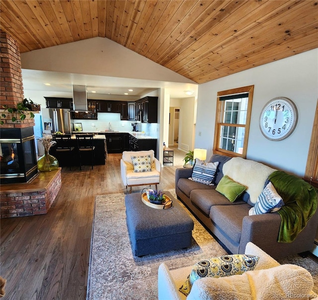 living area with high vaulted ceiling, wood ceiling, a fireplace, and wood finished floors