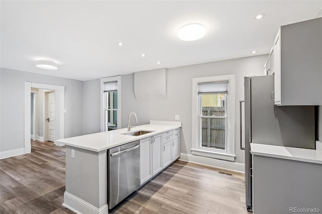 269 Delaware St, Denver, CO 80223 - kitchen featuring appliances with stainless steel finishes, a peninsula, wood finished floors, light countertops, and recessed lighting