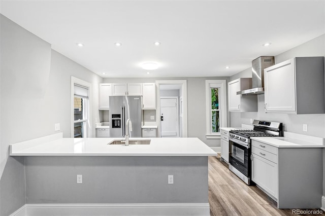 269 Delaware St, Denver, CO 80223 - kitchen featuring appliances with stainless steel finishes, wall chimney range hood, plenty of natural light, light wood-type flooring, and recessed lighting