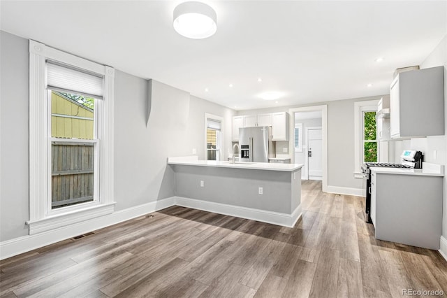 269 Delaware St, Denver, CO 80223 - kitchen featuring high end fridge, range with gas cooktop, light countertops, light wood finished floors, and a peninsula