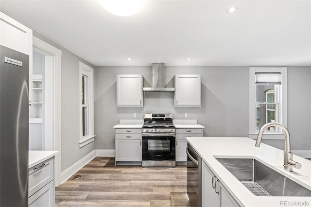 269 Delaware St, Denver, CO 80223 - kitchen featuring stainless steel appliances, wall chimney range hood, light wood-type flooring, light countertops, and recessed lighting