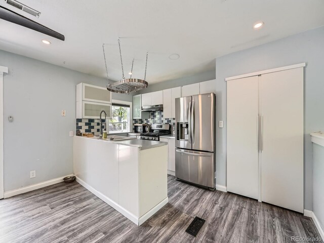 12991 E Idaho Dr, Aurora, CO 80012 - kitchen featuring appliances with stainless steel finishes, a sink, wood finished floors, under cabinet range hood, and a peninsula
