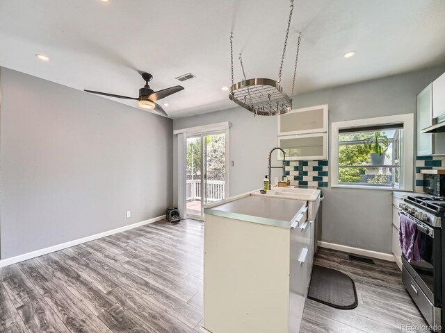 12991 E Idaho Dr, Aurora, CO 80012 - kitchen with stainless steel gas stove, wood finished floors, recessed lighting, a sink, and light countertops