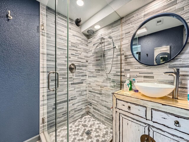12991 E Idaho Dr, Aurora, CO 80012 - bathroom featuring a stall shower, vanity, and tile walls