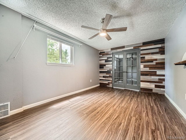 12991 E Idaho Dr, Aurora, CO 80012 - unfurnished living room with a ceiling fan, wood finished floors, french doors, a textured ceiling, and wooden walls
