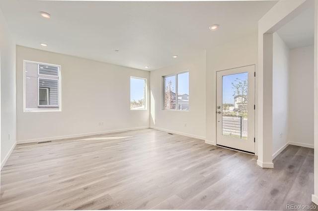 unfurnished room with a healthy amount of sunlight and light hardwood / wood-style floors