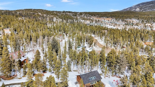 snowy aerial view with a mountain view and a wooded view