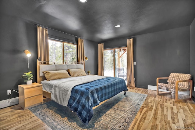 bedroom with access to outside, baseboards, and wood finished floors