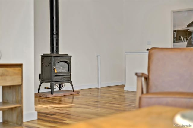 interior space with a wood stove, baseboards, and wood finished floors