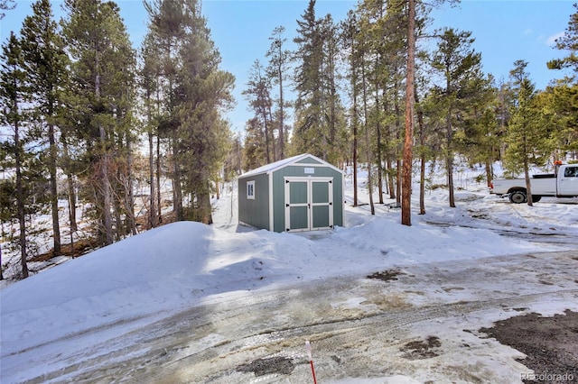 yard covered in snow with an outbuilding and a storage shed