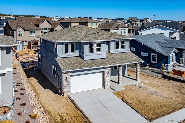 view of front facade with driveway, stone siding, a residential view, roof with shingles, and an attached garage