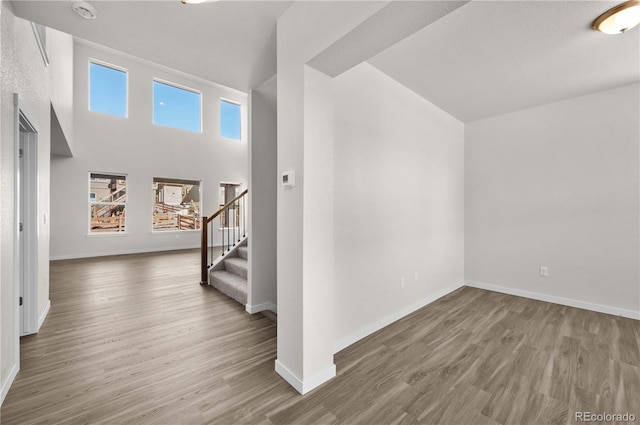 entryway featuring wood finished floors, baseboards, and stairs