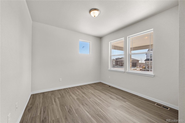 unfurnished room with visible vents, baseboards, and wood finished floors