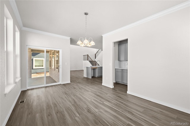 unfurnished dining area featuring crown molding, visible vents, dark wood finished floors, and a notable chandelier