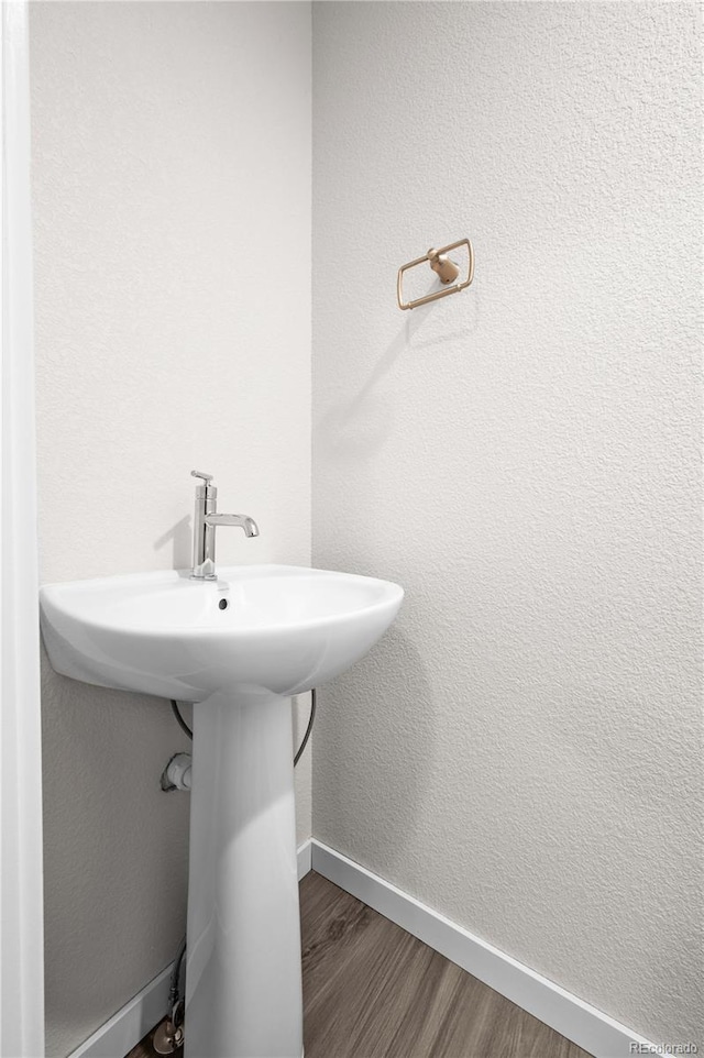 bathroom featuring a sink, baseboards, and wood finished floors