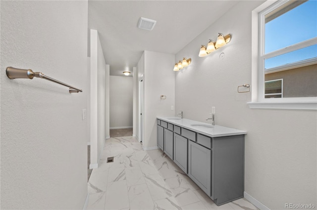 bathroom with double vanity, marble finish floor, baseboards, and a sink