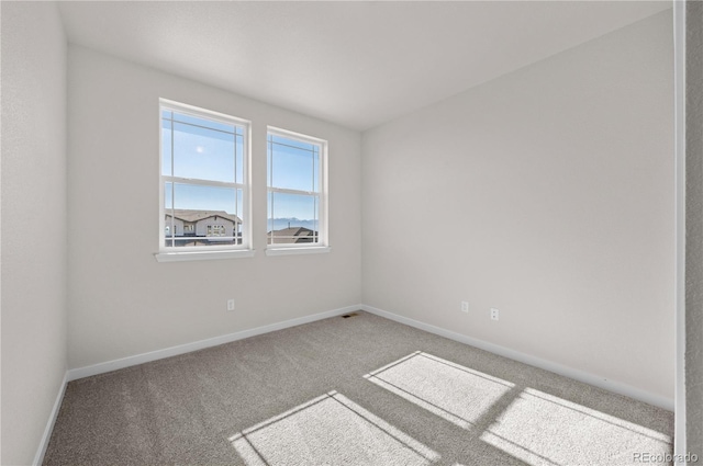 carpeted spare room featuring baseboards