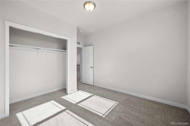 unfurnished bedroom with a closet, light carpet, and baseboards