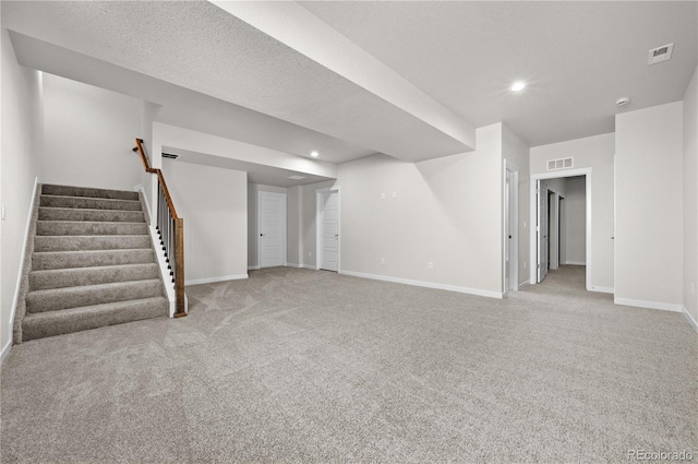 below grade area with baseboards, visible vents, light colored carpet, stairs, and recessed lighting