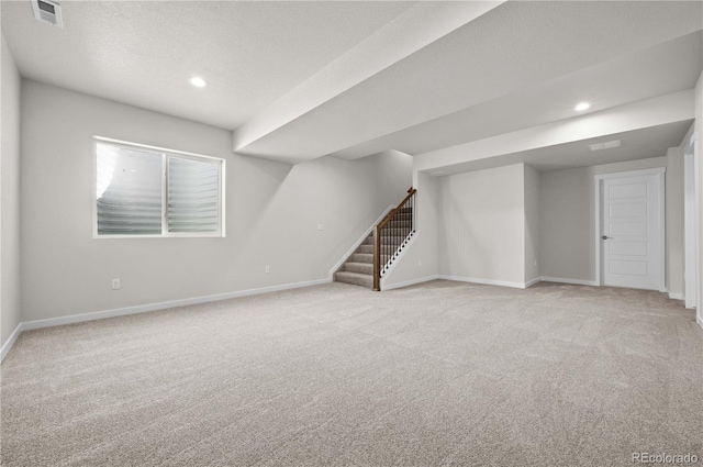 below grade area featuring baseboards, stairs, visible vents, and light colored carpet