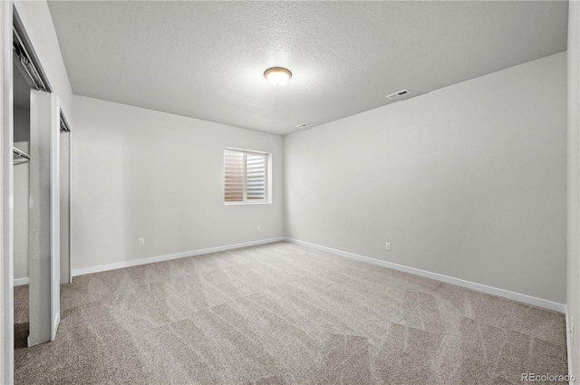 unfurnished bedroom with baseboards, visible vents, a textured ceiling, and light colored carpet