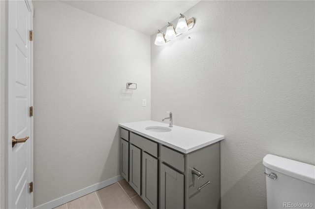 bathroom featuring toilet, tile patterned flooring, vanity, and baseboards