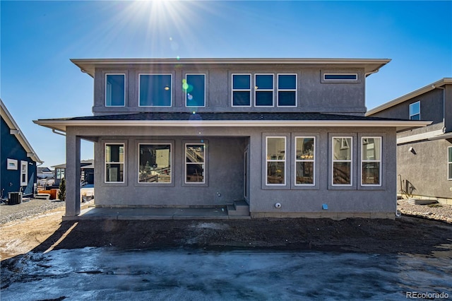 view of front of property with central AC, roof with shingles, and stucco siding