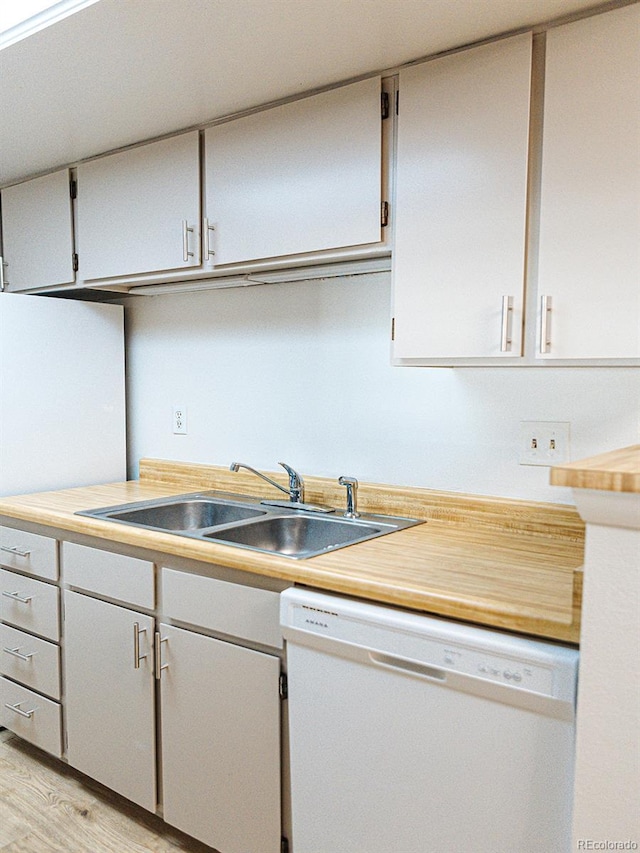 kitchen with light wood finished floors, light countertops, a sink, white cabinetry, and dishwasher